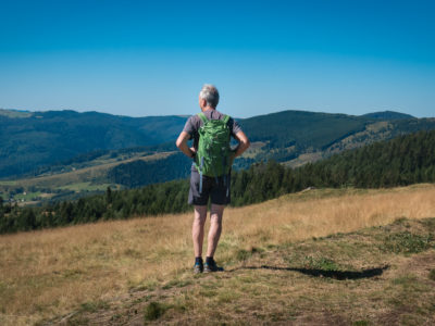 Un randonneur vu de dos regarde les Vosges pendant une randonnée en Alsace