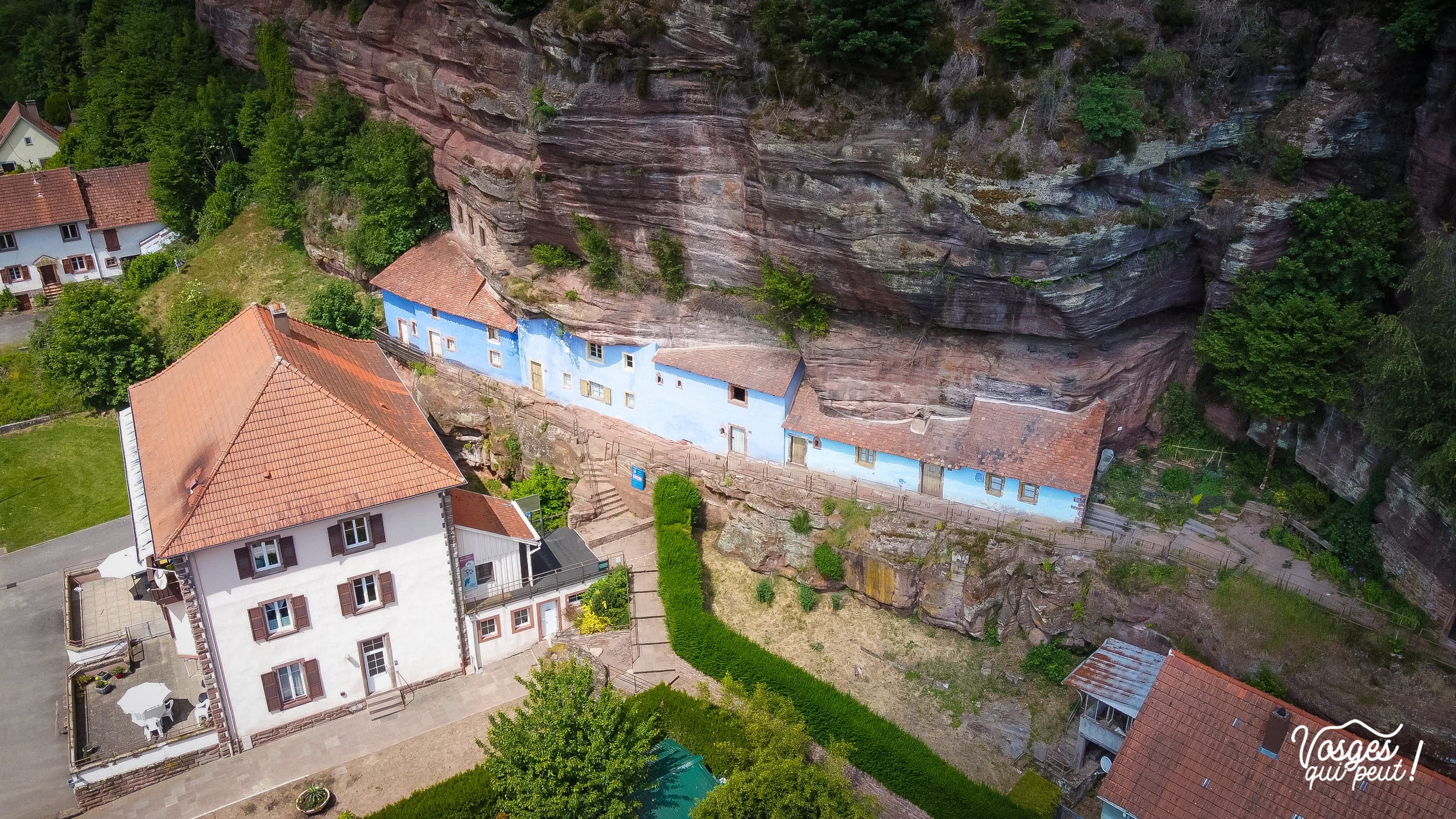 Les maisons des rochers de Graufthal vues du ciel au pied de leur falaise de grès