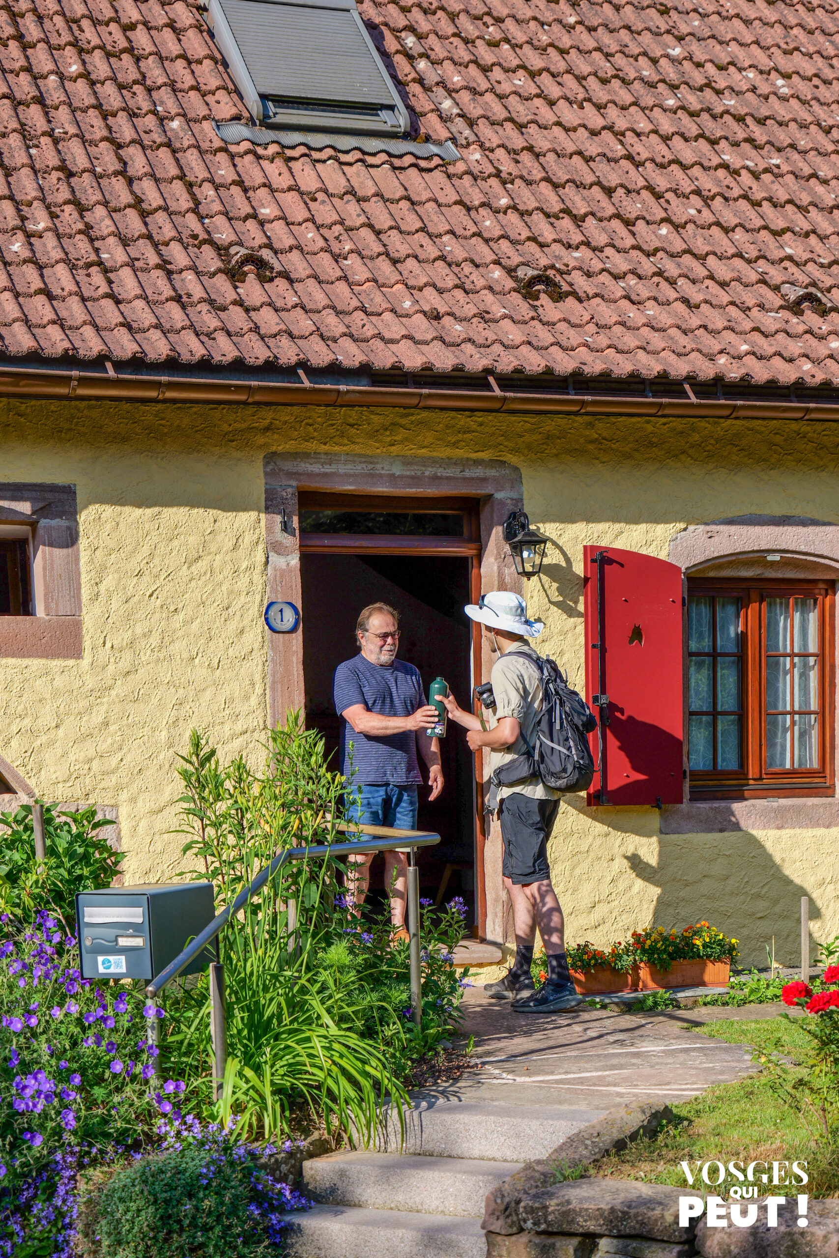 Randonneur remplissant sa gourde chez un habitant de la vallée de la Bruche grâce à Hel'eau La Bruche